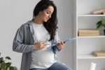 side view pregnant woman working from home with clipboard Understanding Prenatal Testing: What Tests Are Available and What They Can Tell You