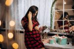female portrait pregnant woman checked shirt poses cozy room with christmas tree 1 Styling Your Baby Bump: Maternity Outfit Ideas for Special Occasions